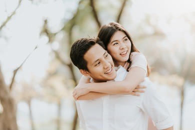 happy young asian couple in love having a good time and embracing in the park