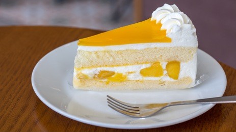 a piece of mango cake isolated in white plate on the wooden