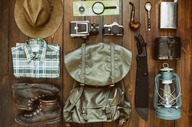 jungle tropical forest, mountains hiking stuff arranged on wooden floor. machete, shirt, clothes, boots, lantern, smoking pipe, hat, map, compass. trekking postcard, poster, banner concept.