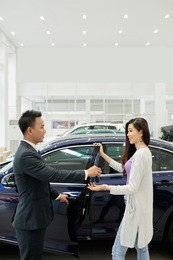 pretty young vietnamese woman taking keys of her new car