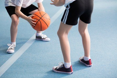 cropped photo of pupils playing basketball in the gym