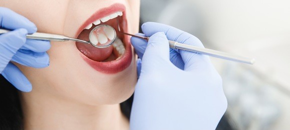 smiling pretty woman is having her teeth examined by dentist in clinic. concept of caries treatment
