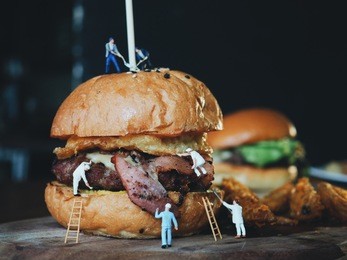 close up miniature people painting color and making a delicious cheese burger.