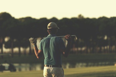 golfer  from back looking to ball and  hole in distance, handsome middle eastern golf player portrait from back with beautiful sunset in background