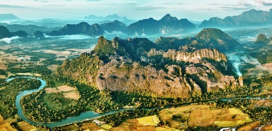 aerial bird's-eye sunrise time view on valley landscape with karst mountains, river and rice fields. laos, vang vieng.