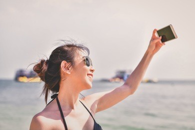 swimsuit concept. beautiful girl wearing a swimsuit playing mobile on the beach. beautiful girl is traveling on the beach. beautiful girls are happy.