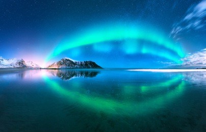 aurora reflected in water. northern lights in lofoten islands, norway. blue sky with polar lights. night landscape with aurora, sea with sky reflection, beach, mountains. polar lights. aurora borealis
