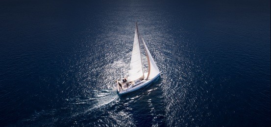sailing ship yachts with white sails at opened sea. aerial - drone view to sailboat in windy condition.