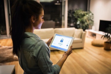 a woman holding a tablet with smart home screen.