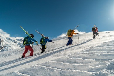 mountaineers walking up along a snowy ridge with the skis in the backpack. skier on the climbing track for freeride-descent. backcountry skiers. ski free rider climbs the slope into deep snow powder. 