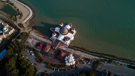 aerial view photo - view of a white floating mosque, the melaka straits mosque, located on the man-made malacca island near melaka city, melaka, malaysia.
