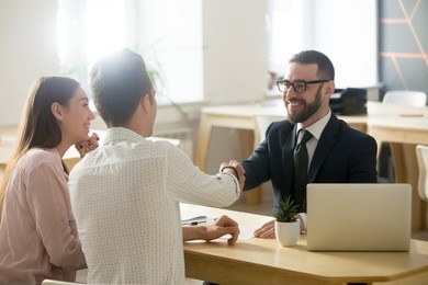 smiling lawyer, realtor or financial advisor handshaking young couple thanking for advice, insurance broker or bank worker and millennial customers shake hands making deal, investment or taking loan