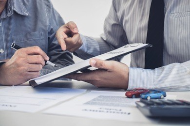 car and home insurance concept, broker agent presenting and consult to customer to decision making sign insurance form agreement, home and car model.