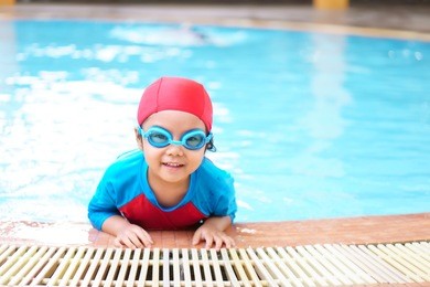asian children cute or kid girl wear swimming suit and goggles on swimming pool and smile with happy fun in water park for learning and training or refreshing and relax with exercise on summer holiday