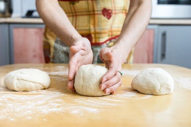 baker hands preparing khachapuri on kitchen table. view on cook making traditional georgian treat with raw dough