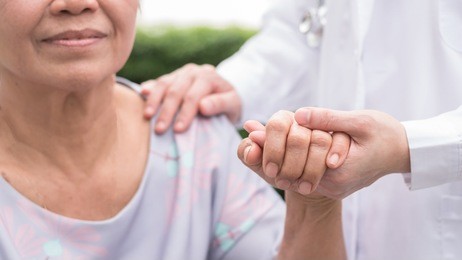 elderly senior patient (aging old adult person) in nursing hospice home holding geriatrician doctor's hand having happy medical health care from hospital carer or caregiver healthcare service