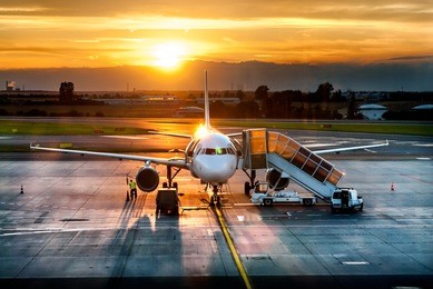 passenger airplane on runway near the terminal in an airport at sunset time. airport land crew doing flight service for passenger airplane at sunset time.