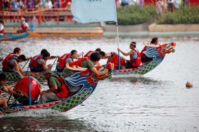 scene of a competitive boat racing in the traditional dragon boat festival in taipei, taiwan, with view of athletes pulling vigorously on their oars and competing strenuously in colorful dragon boats