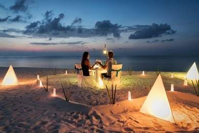 honeymoon couple is having a private, romantic dinner at a tropical beach