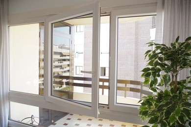 tilt-and-turn white pvc window in living room, opened