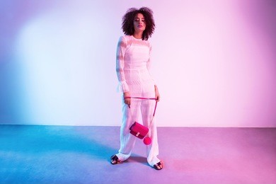fashion portrait of young elegant woman in nice clothes. colored background, neon lights, studio shot. amazing afro hair