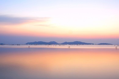 long exposure shot colored sky on sunset time over island and reflection water background.