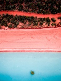 aerial view of a pink sand beach and red dirt road next to roebuck bay in broome, western australia.