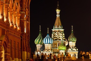st. basil's church in red square, moscow at night with crowds walking around. view as seen from the state historical museum.