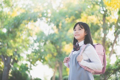 beautiful asian school girl with pink backpack looking up outdoors,back to school concept