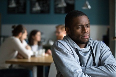 frustrated excluded outstand african american man suffers from bullying or racial discrimination having no friends sitting alone in cafe, sad depressed black guy upset being rejected by white people