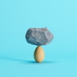 stone put on egg on blue background. minimal creative idea concept.