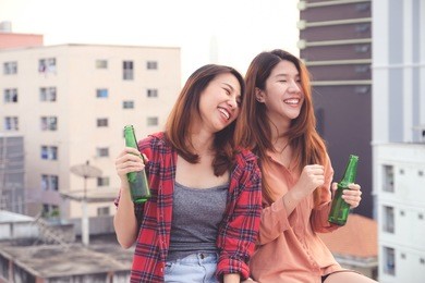 two asian women drinking at rooftop party, outdoors celebration, lgbt couple