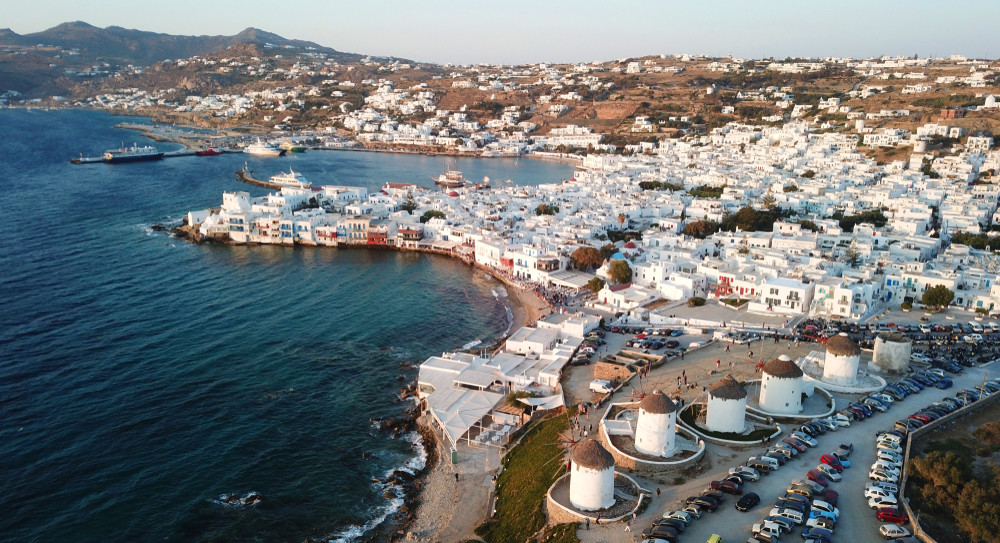 aerial drone, bird's eye view of iconic windmills in chora of mykonos island next to little venice, cyclades, greece