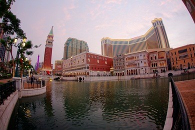 morning scenery of the extravagant exterior of the venetian macao, a luxury hotel & casino resort in macau, china, with beautiful buildings and streets lights by a pool under twilight sky