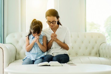 asia woman and little girl  praying on holy bible on white background