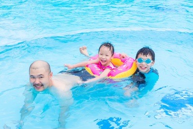 happy asian family playing together in swimming pool