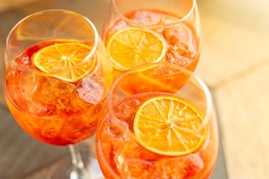 florence, tuscany / italy. - may 4, 2018. italian aperitif  "aperol stpritz" with ice and a slice of orange in  large round glasses on a wooden table in a bar in italy