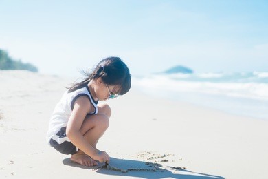 little asian girl playing on the white sand beach.vacation, summer and relax concept.