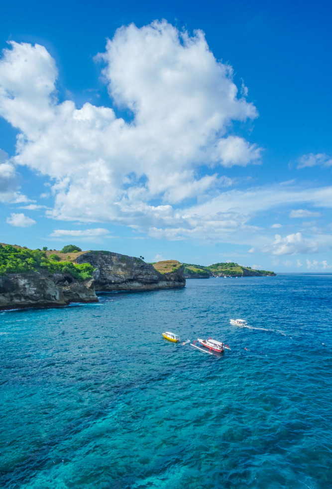 with sea and cliffs, and a boat steaming near to the shoreline