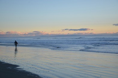 a surfer surfing at the new brighton beach. it's a best spot to visit for sunrise and play amongst the waves under the pier or maybe take a stroll along the top and watch the fishermen.