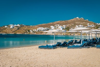 mykonos island, famous ornos beach organized with sun beds emerald clear water beach of ornos in island of mykonos, cyclades, greece