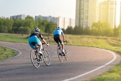 two cyclists riding bikes on special road. triathletes cycling up the hill on bicycles. practicing for triathlon race on country road.