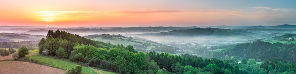 vibrant panoramic sunrise over countryside hills in poland. spring mist and green fields.