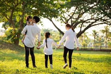 asian family are going out of the house , parents and children were walking hand in hand together a happy in garden.
