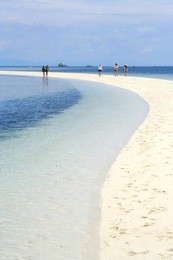 tourist walking along the white sandbar beach of bohol virgin island near panglao, the philippines