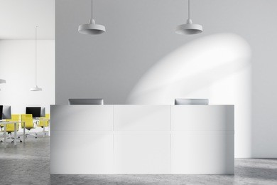 white reception table standing on a concrete floor of an open plan office with bright yellow chairs and rows of computers on the desk. a close up. 3d rendering mock up