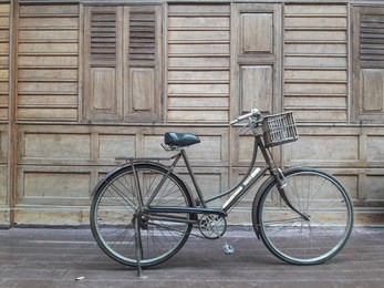 ancient bicycle parked on the front of an ancient wooden house.