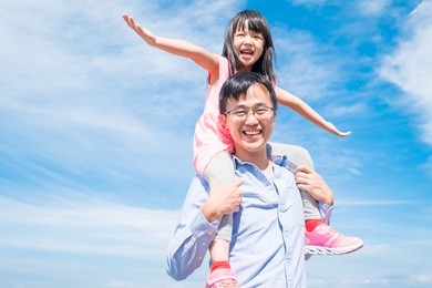 father and daughter smile happily with blue sky