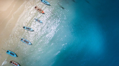 aerial: shoreline with thai long tail fishing and taxi boats parking along the sand beach of thailand
