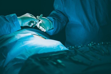 close-up of gloved hands holding surgical tool.surgery team operating in a surgical room.